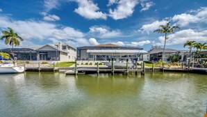 A waterfront property with a marina, modern architecture, and a clear sky. - Tropical Tiki, Heated Pool, Waterfront Gulf Access, Dock your boat, WIFI (Cape Coral)