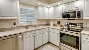 A modern kitchen with white cabinets, stainless steel appliances, a built-in microwave, and a dishwasher. - Tropical Tiki, Heated Pool, Waterfront Gulf Access, Dock your boat, WIFI (Cape Coral)
