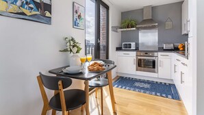 Et moderne køkken med hvide skabe, en emhætte i rustfrit stål og en mikrobølgeovn.