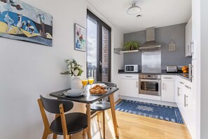 A modern kitchen with white cabinets, a stainless steel range hood, and a microwave. - Bright 1BR with City Views by King's Cross (London)