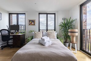 Quarto com cama, escrivaninha, cadeira e planta em vaso.