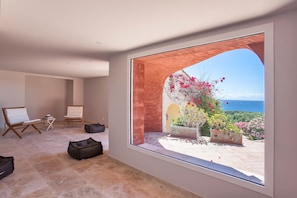 Ein Zimmer mit großem Fenster, zwei Stühlen, einem kleinen Tisch und einem Sitzsack.