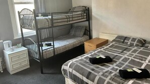Una stanza con un letto a castello, una scrivania, un termosifone e una finestra con tende.