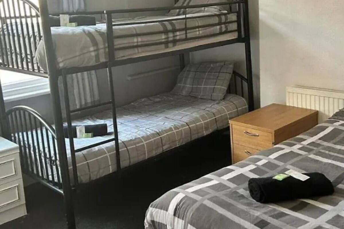 Ein Schlafraum mit Etagenbetten, einem Schreibtisch, einem Nachttisch und einem Bett mit karierter Bettdecke.