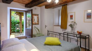 A bedroom with a bed, a bedside table, a mirror, and a window with curtains. - Villa Valgiorgia 9 in Barchi (Terre Roveresche)