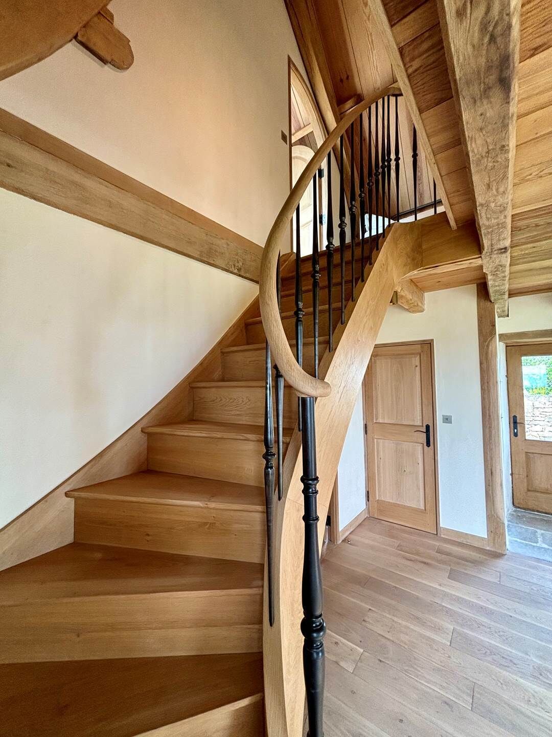A wooden staircase with a curved design and black balusters.