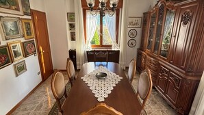 Ein Esszimmer mit Holztisch, Stühlen, einer Pendelleuchte, einem großen Schrank und einem gemusterten Teppich.