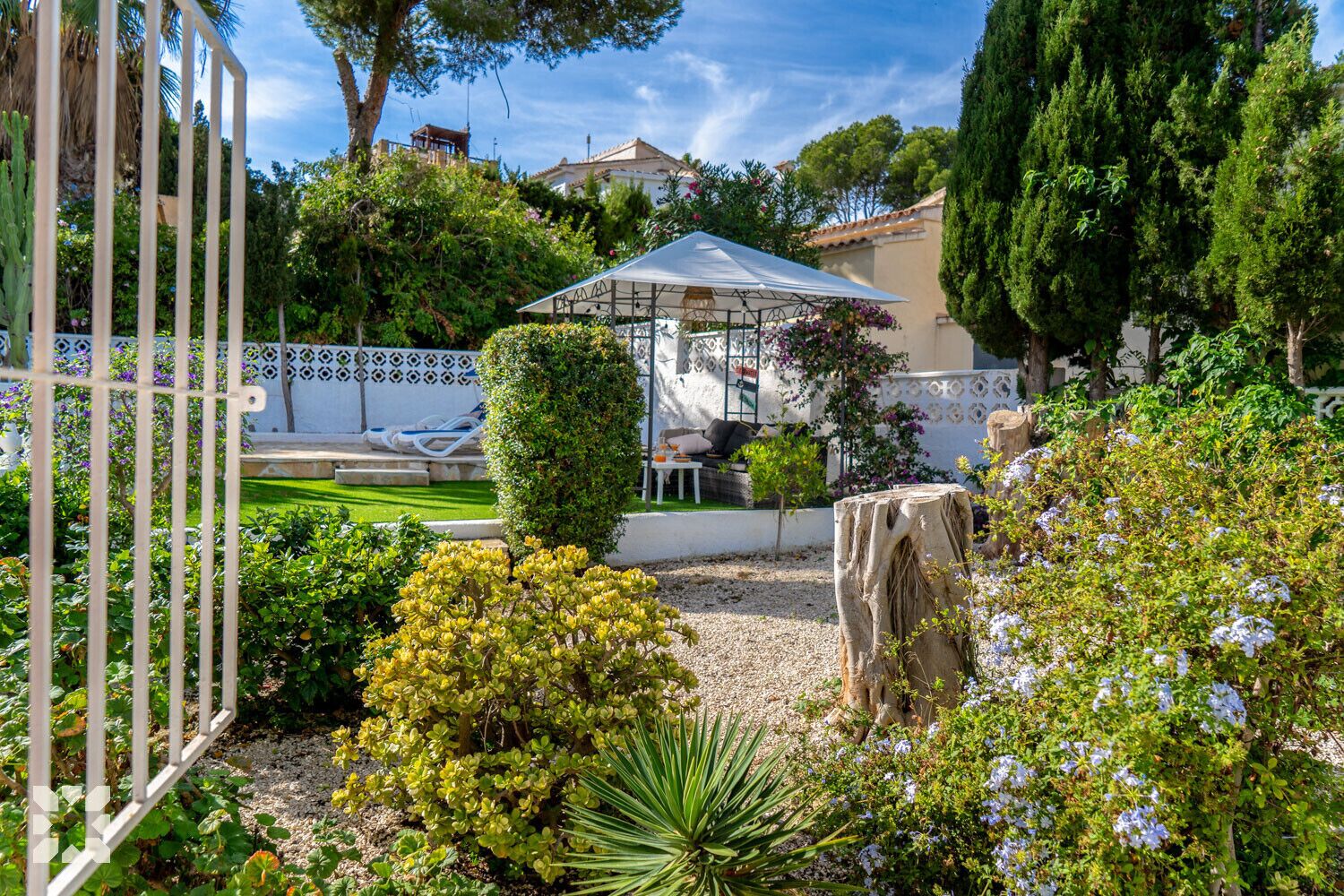 Um jardim com um gazebo, uma piscina e uma cerca branca.