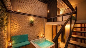 Un área de spa con pared de piedra, un banco de madera, una pequeña piscina y una escalera.