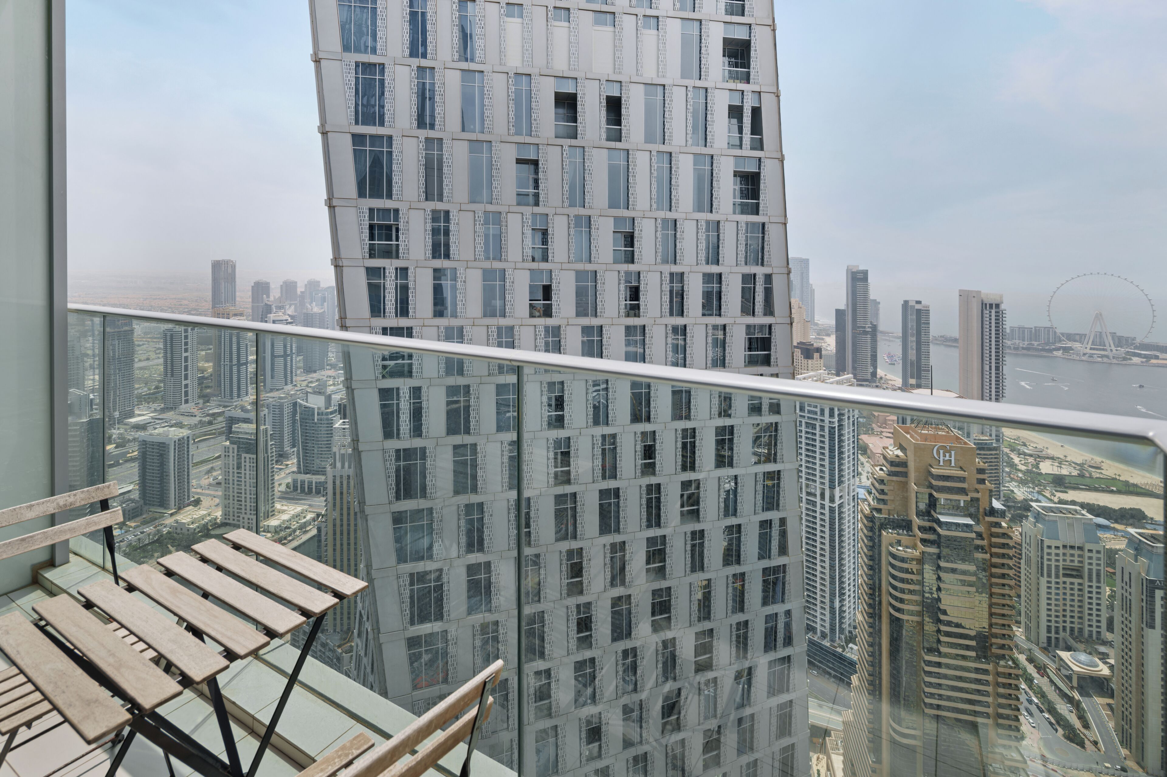 A high-rise building with a modern glass facade, a view of the cityscape, and a Ferris wheel in the distance.