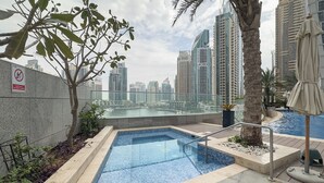 A rooftop pool with a city view, surrounded by palm trees and a no-smoking sign. - Prime 2BR in Damac Heights Marina (Dubai)