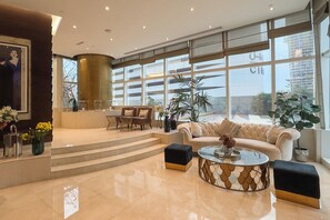 Eine geräumige Lobby mit Sitzgelegenheiten, einer Treppe und großen Fenstern.