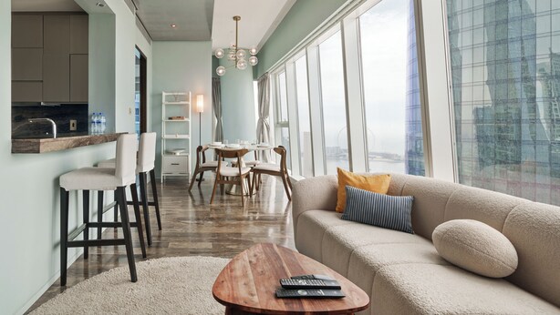 A modern living room with a sofa, coffee table, and dining area. - Prime 2BR in Damac Heights Marina (Dubai)