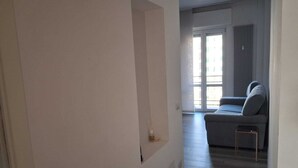 Ein Flur, der in einen Wohnbereich mit einer Couch und einer Heizung führt.