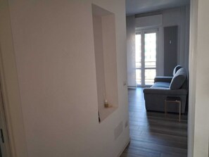 A hallway leading to a living area with a sofa and a radiator. - Design flat in the heart of Tortona District - steps from Fuorisalone events (Milano)