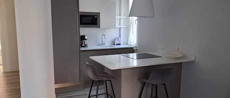 Una cocina moderna con microondas, fregadero y taburetes de bar.