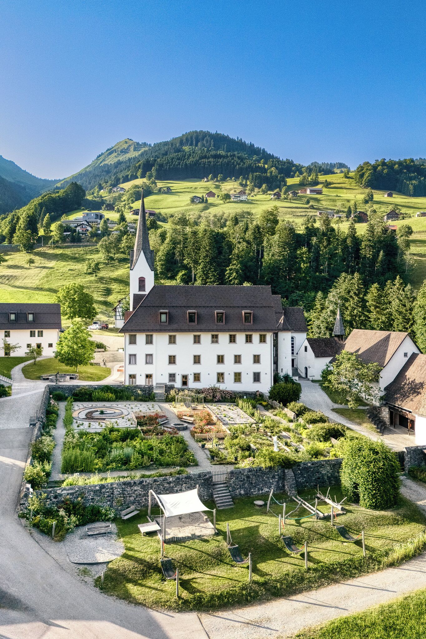 Ein großes, weißes Gebäude mit einem markanten Turm, umgeben von üppigem Grün und einem gepflegten Garten.