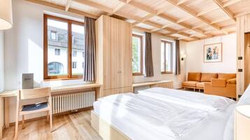 A modern hotel room with a large bed, wooden ceiling, and a view of the outside.