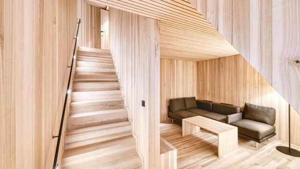 Un interior moderno con una escalera de madera, un sofá y una mesita de centro.