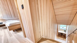 Un interior de madera con una cama, un escritorio y una ventana.