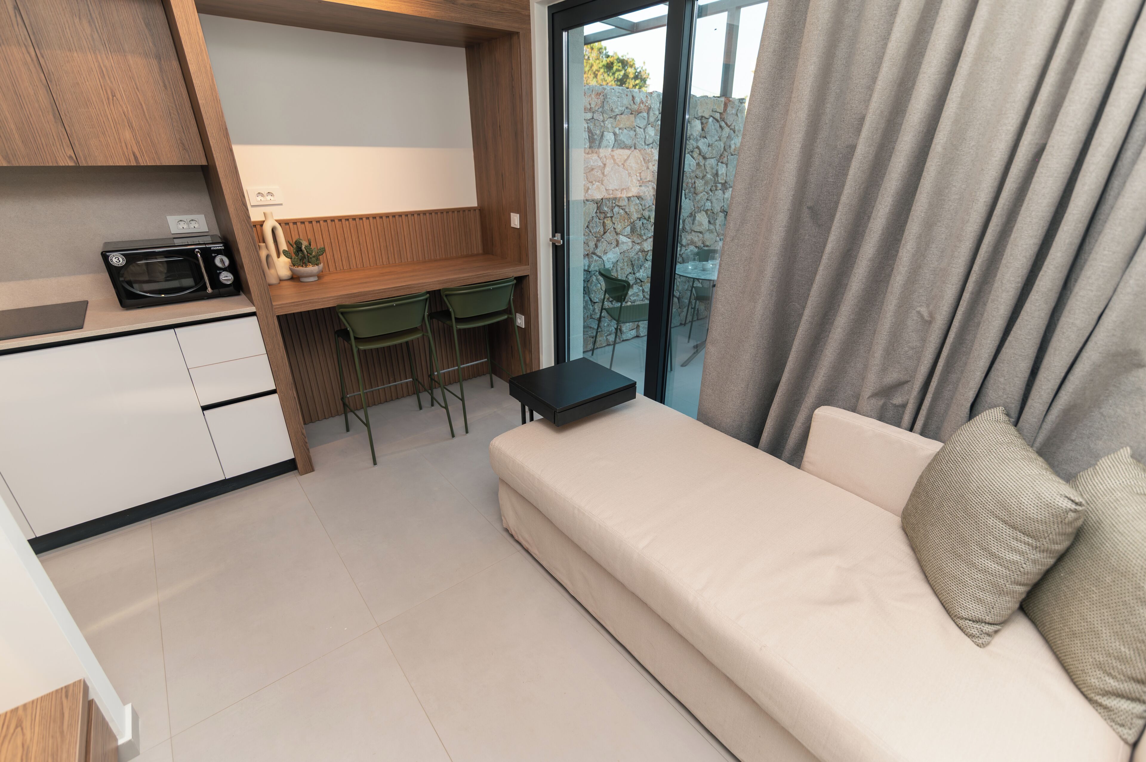 A modern kitchen with a microwave, a wooden countertop, and a dining area with a table and chairs.