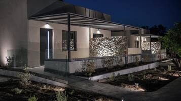 A modern house with a covered patio, stone wall, and garden.