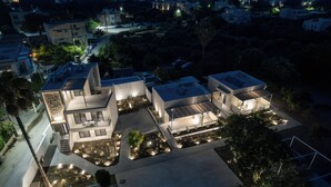 A modern residential complex with multiple connected houses, featuring outdoor lighting and landscaped gardens.