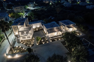 Un moderno complejo residencial con varias casas conectadas, iluminación exterior y jardines ajardinados.