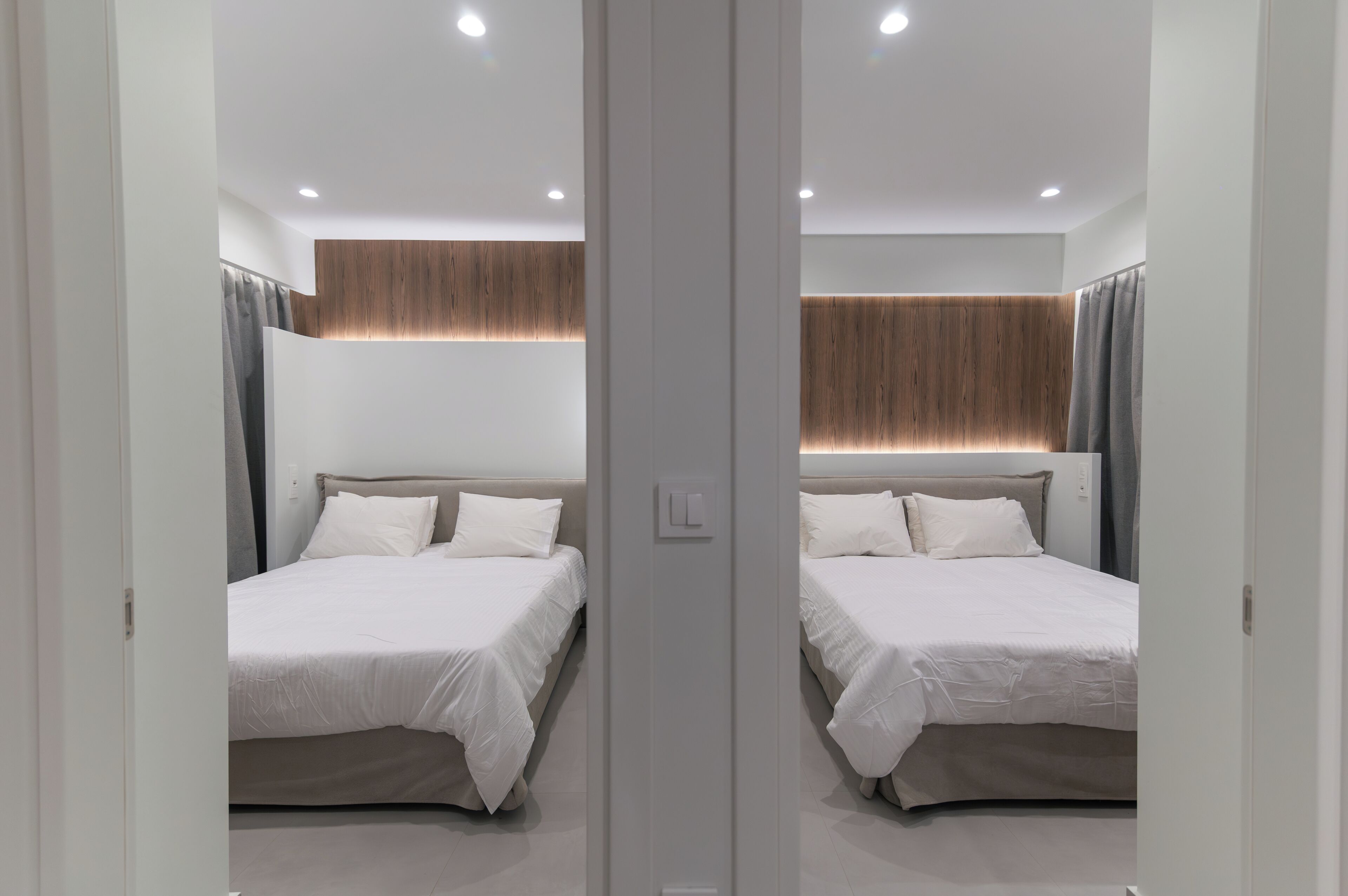 Ein Zimmer mit Spiegel, zwei Betten, einer Holzwand und einem Lichtschalter.