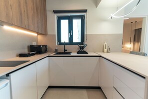 Una cocina moderna con horno empotrado, un fregadero y una ventana con persianas.