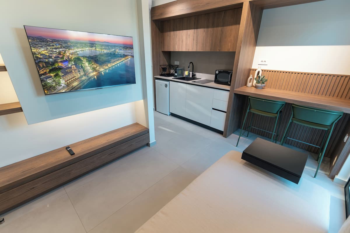 Een moderne keuken met een ingebouwde magnetron, spoelbak en een kleine eethoek met een bankje.