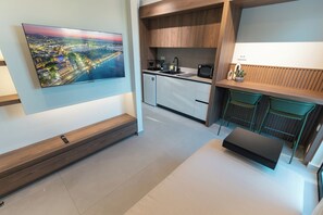 A modern kitchen with a built-in microwave, sink, and a small dining area with a bench.