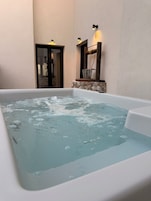 Una bañera de hidromasaje con agua, una pared de piedra y una puerta.