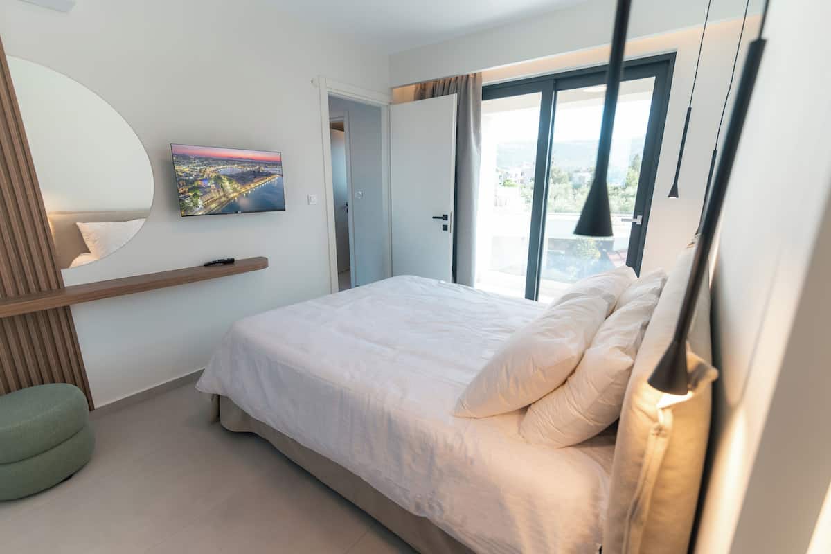 Een slaapkamer met een bed, een televisie, een raam en een deur.