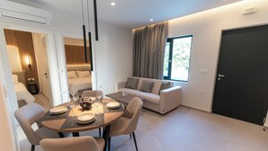 A modern living room with a dining area, a sofa, a large window, and a door.