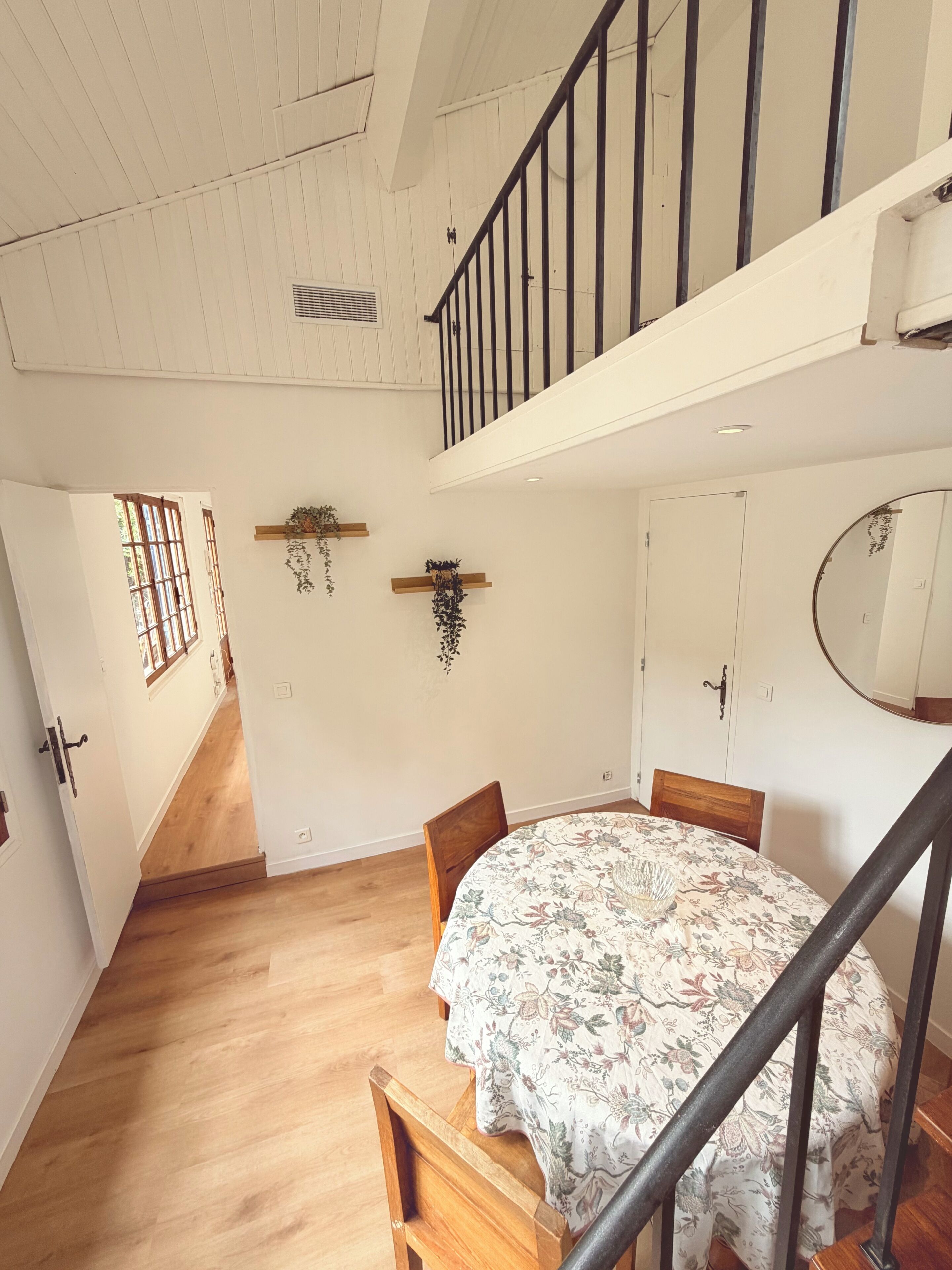 Ein Zimmer mit einem Bett, Holzboden, weißen Wänden, einer Treppe und einer Tür.