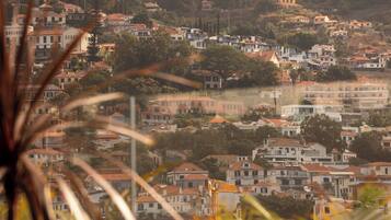 A hillside residential area with multiple buildings, some with red roofs, and a clear view of the landscape.