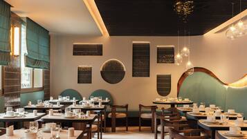 A restaurant interior with multiple dining tables, chairs, and a variety of lighting fixtures.
