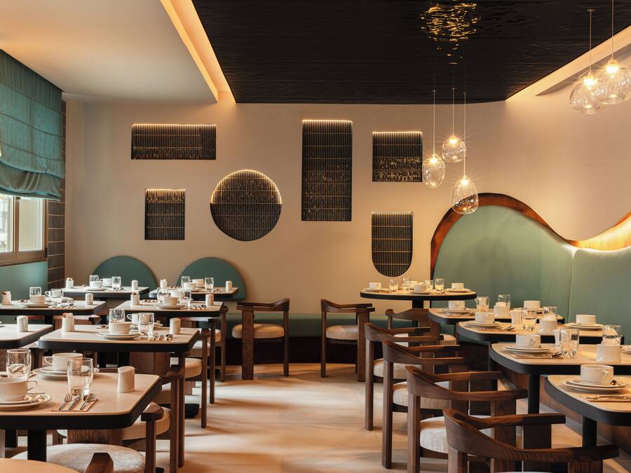 A restaurant interior with multiple dining tables, chairs, and a variety of lighting fixtures.