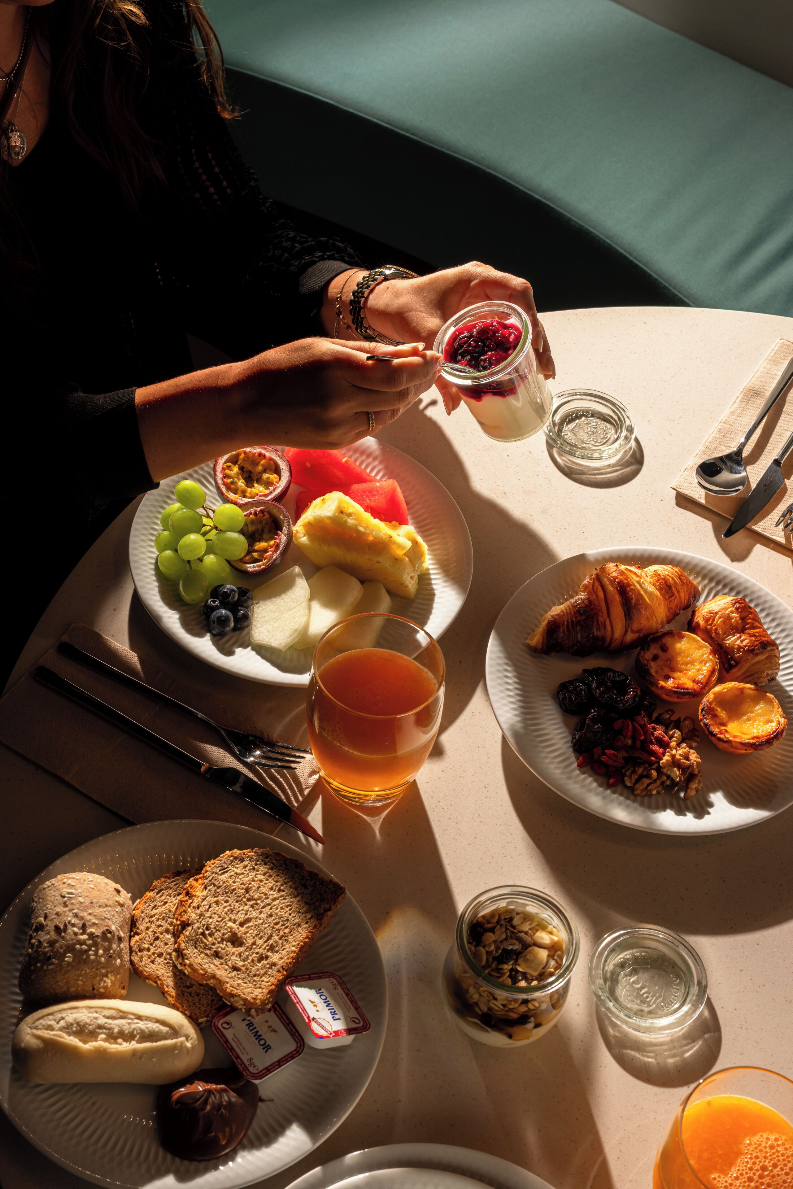 A breakfast setting with plates of food, a glass of juice, and a cup of tea.
