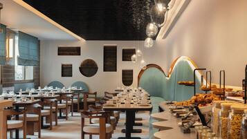A restaurant interior with multiple dining tables, chairs, and a variety of food items displayed on the counter.