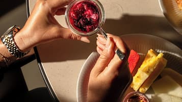 Een tafel met een bord fruit, een glas rode drank en een sneetje brood.