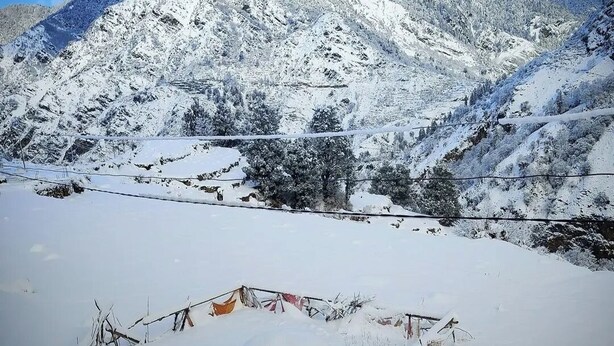 A hand holding a mug, a snow-covered landscape, and a mountain range in the background. - Divine Home stay  (Rajgarhi)