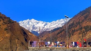 A mountainous landscape with a snow-capped peak in the background, a fence with hanging laundry, and a streetlight. - Divine Home stay  (Rajgarhi)