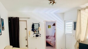 A living room with a sofa, a wooden coffee table, a mirror, and a door leading to a bedroom. - Spacious T3 400m from Anse à l'Ane beach (Les Trois Ilets) (Les Trois-Îlets)