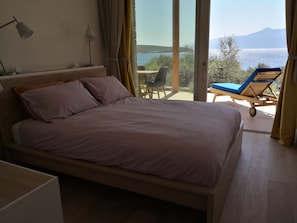 Ein Schlafzimmer mit Bett, Schreibtisch, Stuhl und Meerblick.