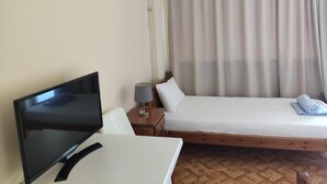 A hotel room with a bed, a TV, a lamp, and an air conditioning unit. - Nicolas (South Pelion)