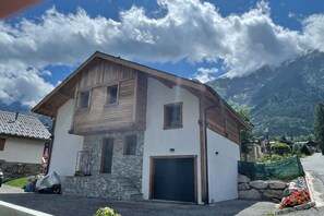 Ein zweistöckiges Gebäude mit einer Steinauffahrt, einer Garage und einem Berg im Hintergrund.