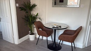 A room with a round table, two chairs, a potted plant, a mirror, and a door. - Near Etihad/coop Live - Parking - Wifi - Sleeps 4 (Manchester)