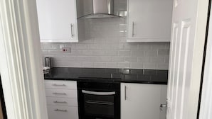 A compact kitchen with white cabinets, a black oven, and a tiled backsplash. - Near Etihad/coop Live - Parking - Wifi - Sleeps 4 (Manchester)